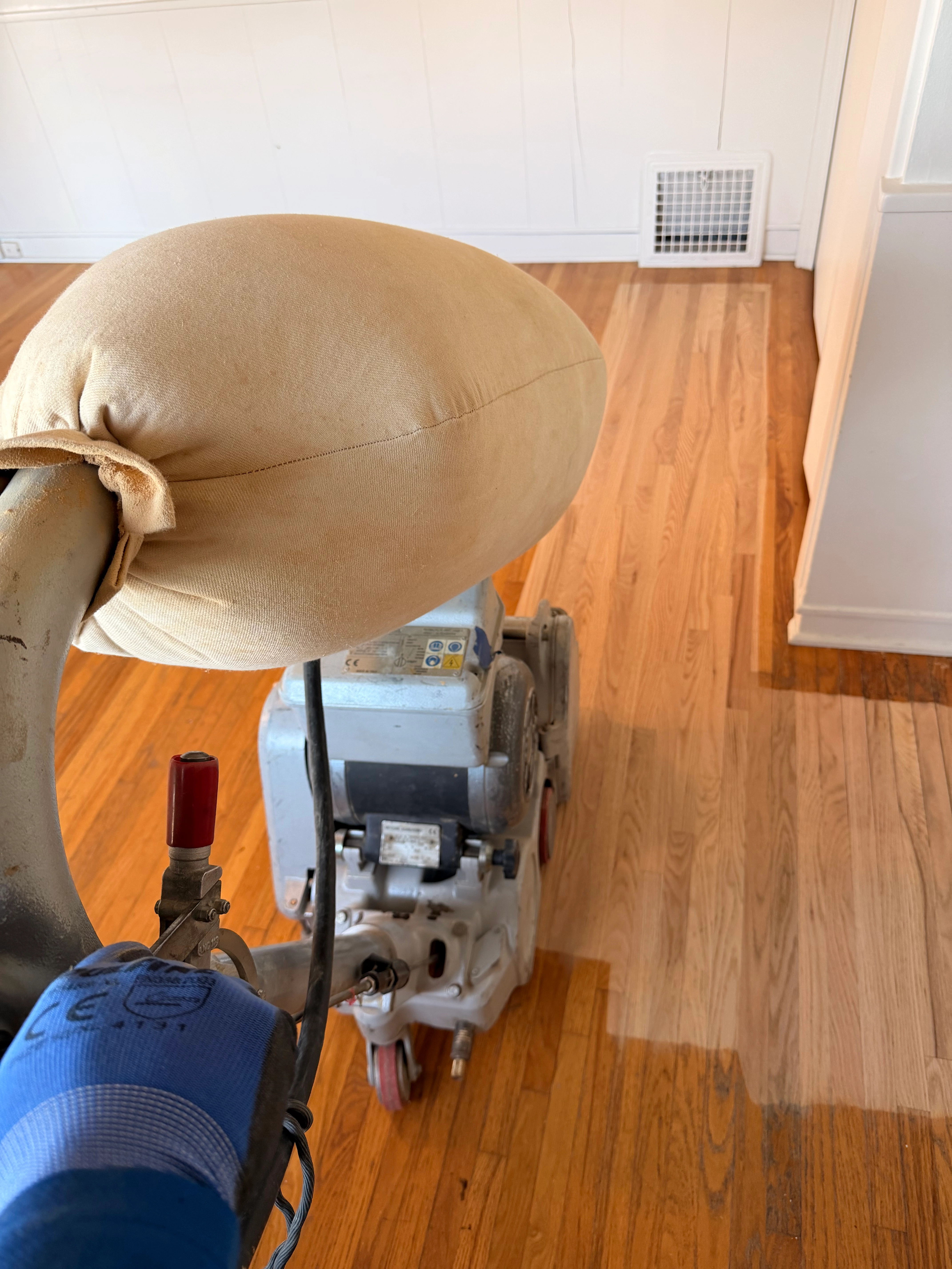 Mid-refinishing hardwood floor showing freshly sanded wood ready for stain